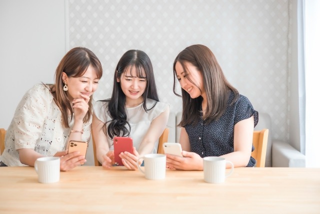 3人の女性がスマホをみながらお茶している様子